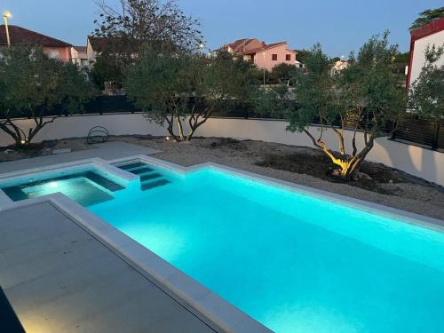 a blue swimming pool in a yard with trees at Family friendly house with a swimming pool Biograd na Moru, Biograd - 23272 in Biograd na Moru