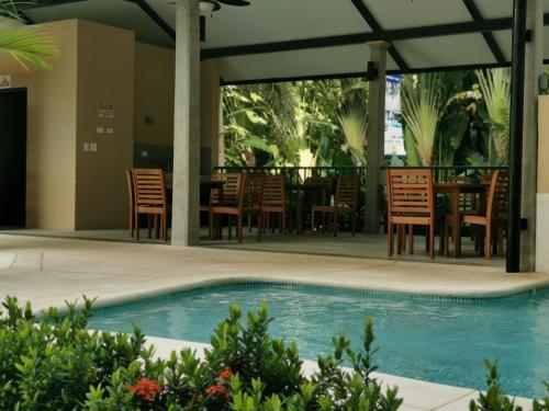 a pool with chairs and a table and a table and chairs at Our Paradise - Jaco Apartment in Jacó