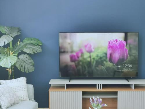 a flat screen tv sitting on a stand with purple flowers at Our Paradise - Jaco Apartment in Jacó