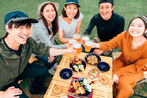 a group of people sitting around a picnic table with food at JYUGON KARISOME Nago Okinawa ジュゴンかりそめ 名護沖縄 in Motobu