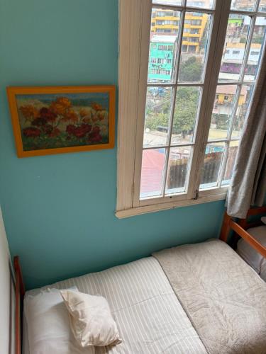 a bedroom with a bed next to a window at BbCasita Yellow in Valparaíso