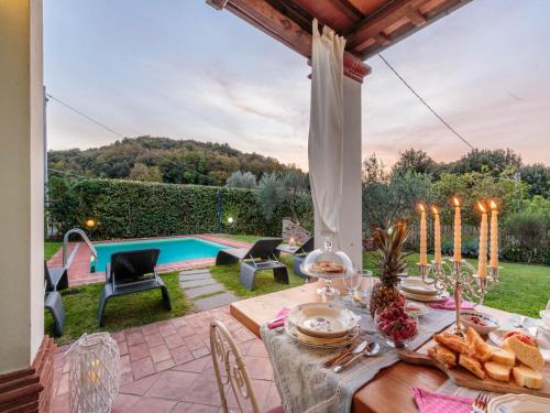 a table with food and candles on a patio with a pool at Farmhouse in Tuscany with Pool and Scenic Views in Chiatri