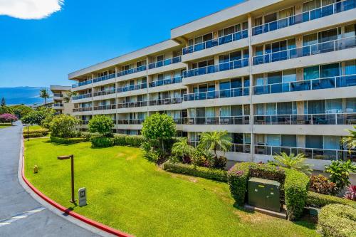 an apartment building with a lawn in front of it at Renovated Condo - 3 Min Walk to Toes in the Sand! in Wailea