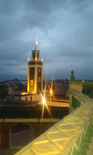a building with a lighthouse in a city at night at Riad Malak in Meknès