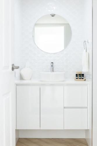a white bathroom with a sink and a mirror at Top of The Mark - Top Floor Apartment, Free Parking in Gold Coast