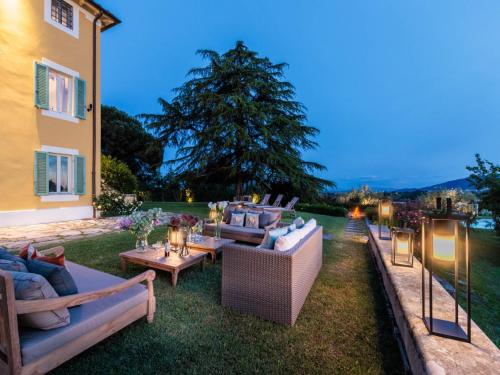 a backyard with couches and tables and a tree at 10 Bedrooms Villa in Lucca with pool in Montecarlo