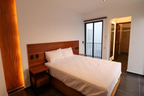 a bedroom with a white bed with a wooden headboard at Palmas Luxury Apartment 106 in Oaxaca City