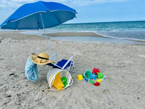 a blue umbrella and a chair on a beach at Steps to the Sand - Private Beach Access & BBQ Grill in Indialantic