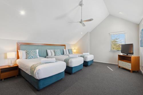 a bedroom with two beds and a flat screen tv at Seashells Mandurah in Mandurah
