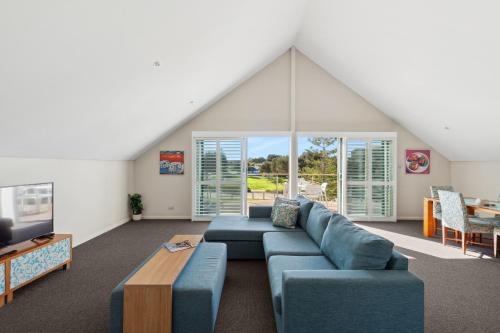 a living room with a blue couch and a table at Seashells Mandurah in Mandurah