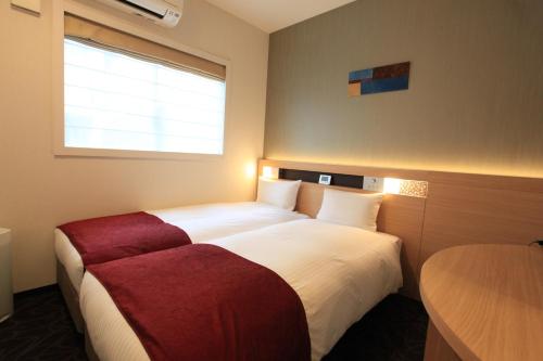 a hotel room with two beds and a table at Urban Hotel Kyoto Nijo Premium in Kyoto