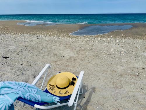 a beach chair with a hat on the beach at Steps to the Sand - Private Beach Access & BBQ Grill in Indialantic