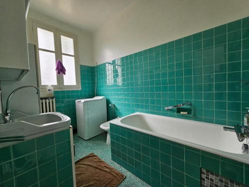 La salle de bains est pourvue de carrelage vert, d'une baignoire et d'un lavabo. dans l'établissement Jolie maison vendéenne, animaux sur demande, proche plage - FR-1-476-52, à La Faute-sur-Mer