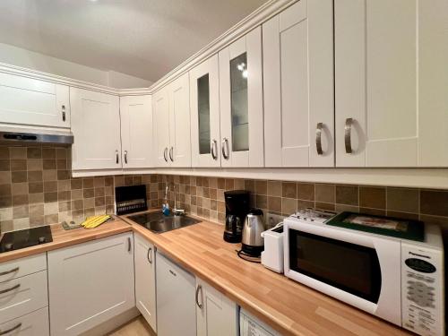 une cuisine avec des armoires blanches et un micro-ondes dans l'établissement Charmant T2 à Arcachon, Proche Plage et Centre, Parking Privé, TV, WIFI, Terrasse - FR-1-319-506, à Arcachon