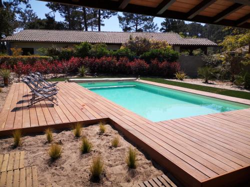 une piscine avec une terrasse en bois à côté d'une maison dans l'établissement Grande maison landaise avec piscine privée, proche plage, pour 8 personnes à Biscarrosse - FR-1-319-398, à Biscarrosse-Plage