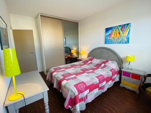 une chambre avec un lit et une table avec une lampe dans l'établissement Appartement Élegant avec Balcon, Garage et WiFi en Bord de Mer - FR-1-92-889, à Les Sables-dʼOlonne
