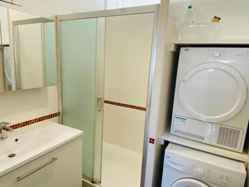 une salle de bain avec une machine à laver et un lavabo dans l'établissement Appartement Élegant avec Balcon, Garage et WiFi en Bord de Mer - FR-1-92-889, à Les Sables-dʼOlonne