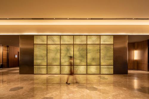 a person walking in front of a wall of glass at 成都高新电子科大桔子水晶酒店 in Chengdu