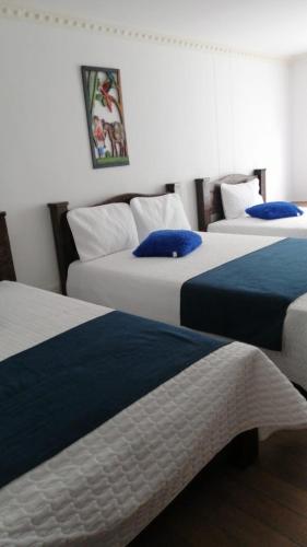 a room with three beds with blue and white at Casa Nova Hotel campestre in Circasia