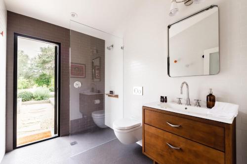 un bagno con lavandino, WC e specchio di Marquee By AvantStay Modern Stylish Estate w Pool Entertainers Courtyard a Boyes Hot Springs