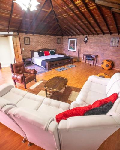a living room with white couches and a bed at Casa Nova Hotel campestre in Circasia