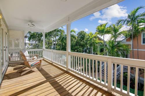 a porch with a rocking chair and palm trees at Coral Palm by AvantStay Key West Walkable Gated Community Shared Pool in Stock Island