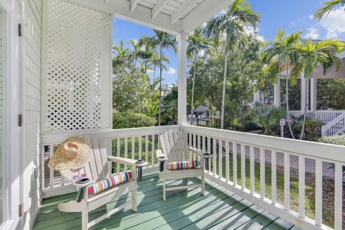 a white porch with two chairs and a table at Coral Palm by AvantStay Key West Walkable Gated Community Shared Pool in Stock Island