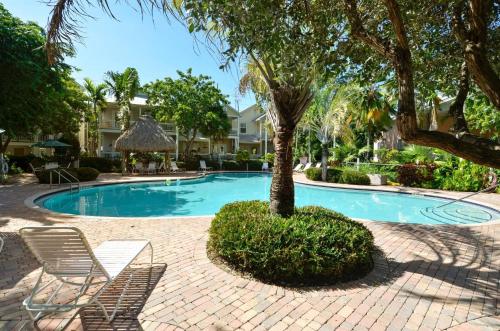 a swimming pool with a palm tree and chairs at Coral Villa by AvantStay Close 2 DT Key West Shared Pool Patio in Stock Island