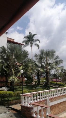 a white fence with palm trees in a park at Casa Nova Hotel campestre in Circasia