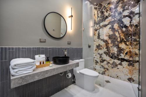a bathroom with a sink and a toilet and a mirror at Europa Suites Medellin in Medellín
