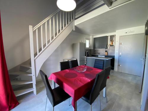 une salle à manger avec une table rouge et des chaises noires dans l'établissement Appartement rénové 2** à 5 min de la plage avec parking et balcon, idéal pour 4 personnes - FR-1-732-10, à Argelès-sur-Mer