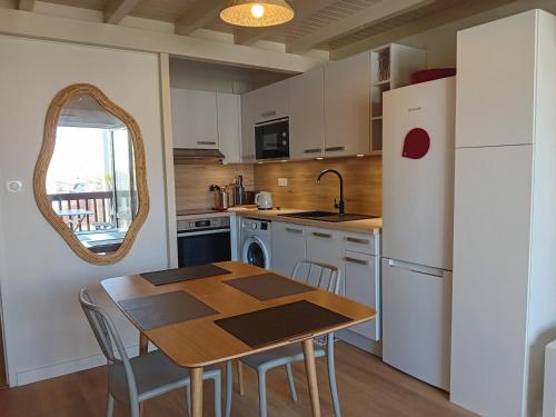 une cuisine avec une table et un réfrigérateur blanc dans l'établissement Seignosse : Appartement rénové à pied des plages avec climatisation - FR-1-239-1126, à Seignosse