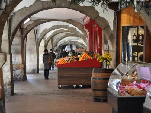 une femme qui traverse un marché avec un stand de fruits dans l'établissement Appartement rénové proche lac avec parking - FR-1-432-93, à Annecy