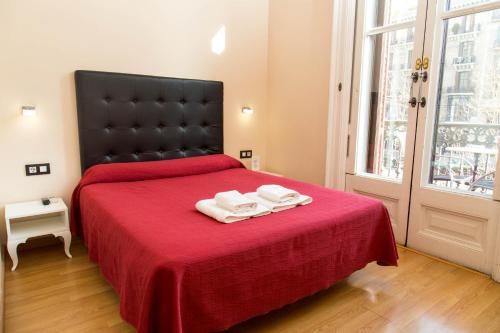 a bedroom with a red bed with two towels on it at Center Gran Via in Barcelona