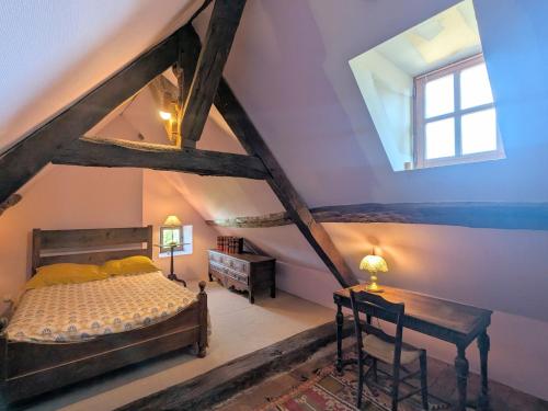 a attic bedroom with a bed and a window at Manoir du 15ème siècle avec piscine dans le Parc Naturel Régional de la Brenne - FR-1-591-740 in Mauvières