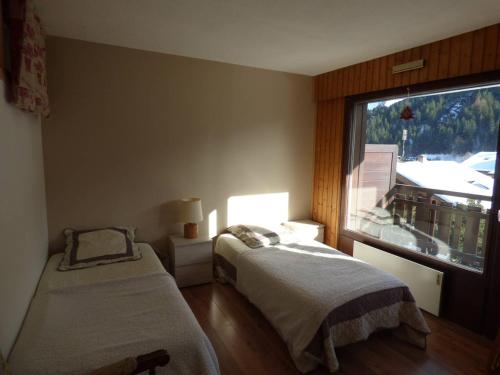 une chambre avec deux lits et une grande fenêtre dans l'établissement Appartement lumineux 64m², 6 personnes, vue sur montagnes - FR-1-458-230, au Grand-Bornand