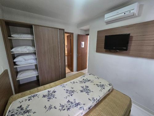 a bedroom with a bed and a tv and towels at Apartamentos em Rio Quente com maravilhosa área de lazer e excelente localização in Rio Quente