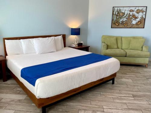 a bedroom with a large bed and a green chair at Beachgate Condo Suites and Hotel 512AB condo in Port Aransas