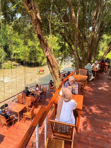 a group of people sitting at tables on a deck at Puunee Wild River Villa's Borobudur in Borobudur