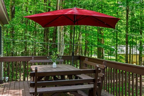 a picnic table with a red umbrella on a deck at Tawny and Peaceful Game Room Firepit PatioDeck Workspace in Arrowhead Lake