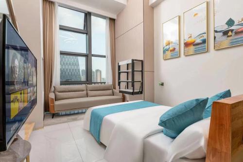 a bedroom with a bed and a tv and a couch at 深圳华尔曼欢朋酒店公寓 罗湖水贝珠 宝城店 in Shenzhen