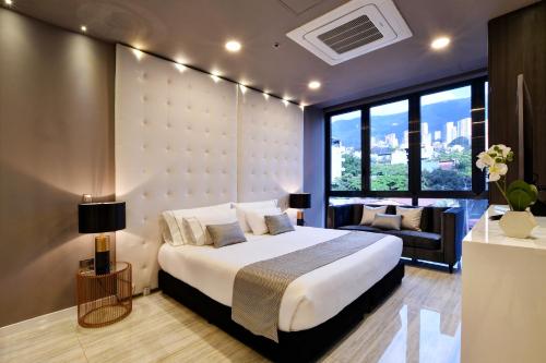 a bedroom with a large white bed and a couch at Europa Suites Medellin in Medellín
