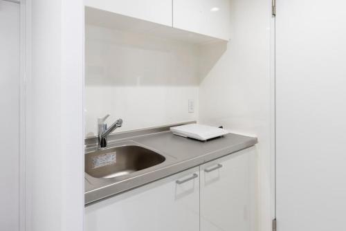 eine Küche mit Spüle und weißen Schränken in der Unterkunft AMP FLAT Daimyo 702 in Susakiuramachi