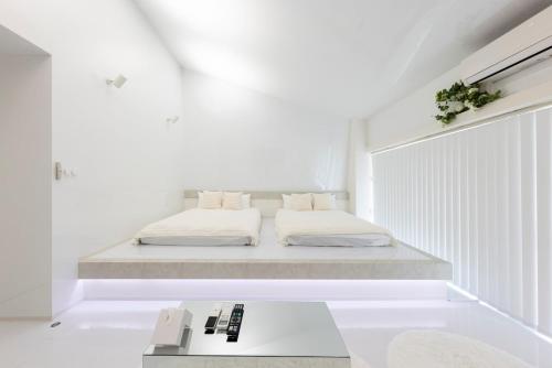 ein weißes Schlafzimmer mit einem Bett und einem Tisch in der Unterkunft AMP FLAT Daimyo 702 in Susakiuramachi