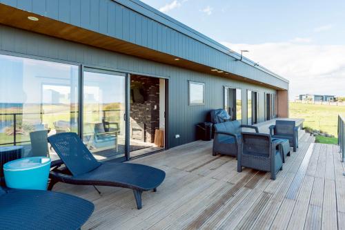 a deck with chairs and tables on a building at Luxury Absolute Ocean View Lodge in Waverley