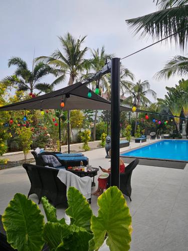 a patio with a black umbrella and a pool at Villa Minou Ta khmau in Phnom Penh