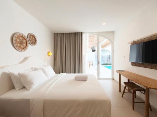 a bedroom with a white bed and a television at Villa Vinodayan Uluwatu by LODGELINK BALI in Uluwatu