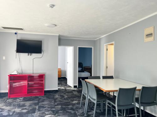 a room with a table and chairs and a tv at Beetham Park Motel in Hamilton