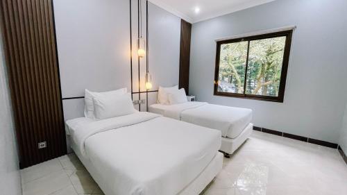 a hotel room with two beds and a window at Damar Langit Resort in Cisarua