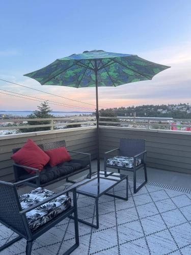 a patio with a couch and chairs and an umbrella at Gorgeous Queen Anne Townhouse - Rooftop Deck! in Seattle